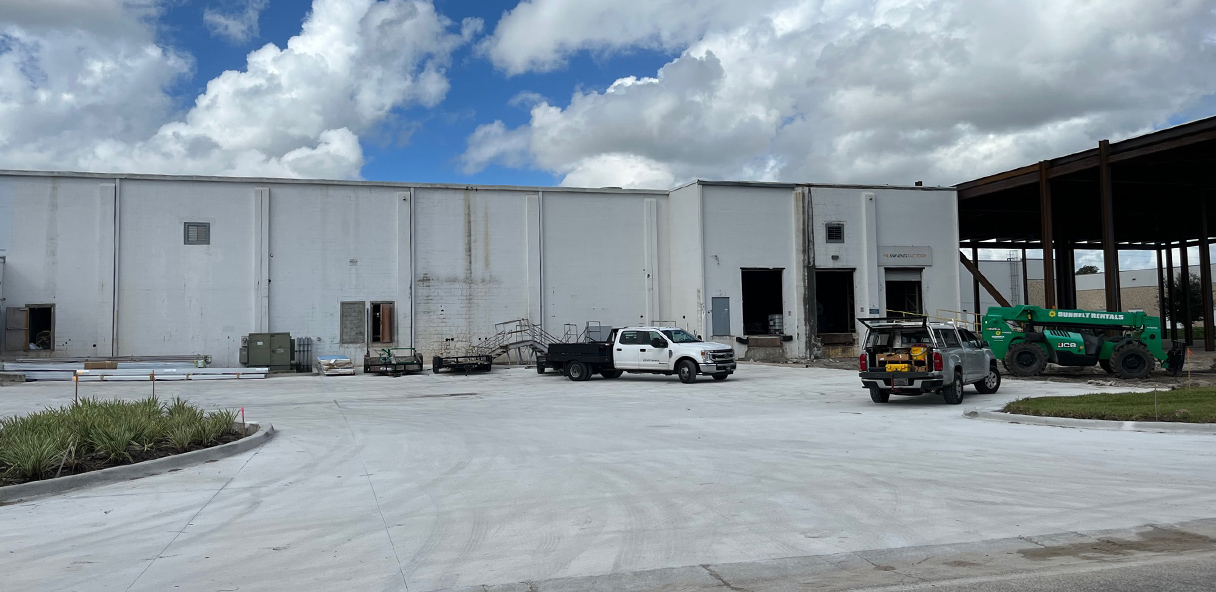 Photo of large industrial building with trucks in the driveway.